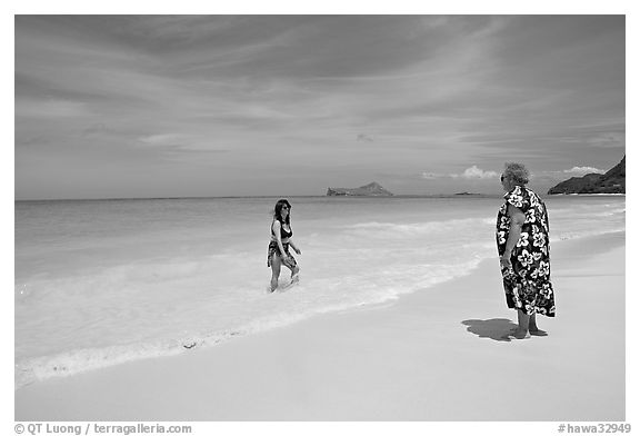 Two women, the older in hawaiian dress, on Waimanalo Beach. Oahu island, Hawaii, USA (black and white)