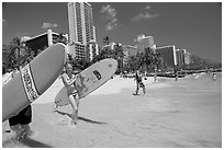 Women carrying surfboards into the water, Waikiki Beach. Waikiki, Honolulu, Oahu island, Hawaii, USA ( black and white)