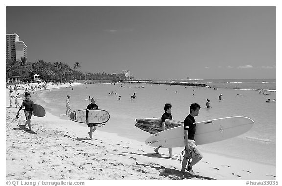 Men walking on Waikiki Beach with surfboards. Waikiki, Honolulu, Oahu island, Hawaii, USA (black and white)