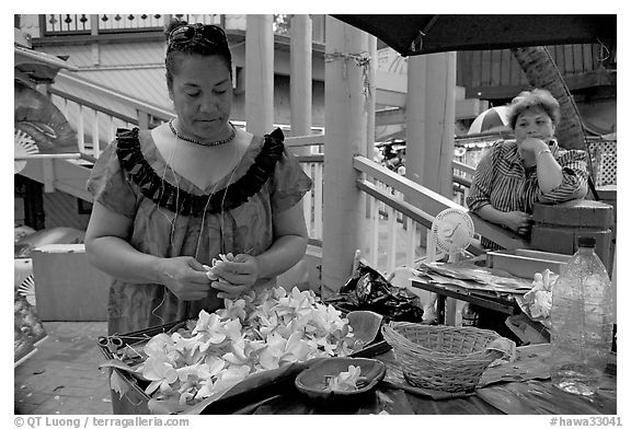 Woman preparing a fresh flower lei, with another woman looking, International Marketplace. Waikiki, Honolulu, Oahu island, Hawaii, USA (black and white)