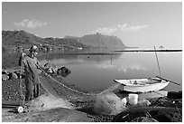 Fisherman pulling out net out of small baot, Kaneohe Bay, morning. Oahu island, Hawaii, USA (black and white)