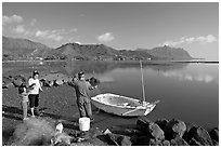Fisherman and family pulling out net out of small baot, Kaneohe Bay, morning. Oahu island, Hawaii, USA ( black and white)