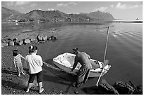 Fisherman with family and small baot, Kaneohe Bay, morning. Oahu island, Hawaii, USA ( black and white)
