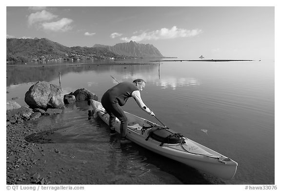 Man loading sea kayak for a fishing trip, Kaneohe Bay, morning. Oahu island, Hawaii, USA