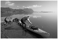 Man loading sea kayak for a fishing trip, Kaneohe Bay, morning. Oahu island, Hawaii, USA ( black and white)