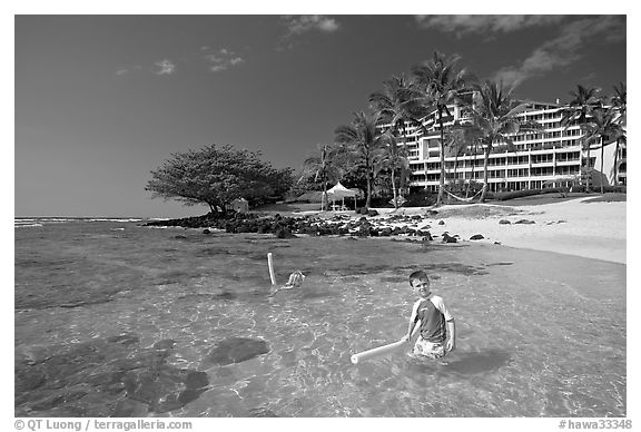 Children on Puu Poa Beach and Princeville Hotel. Kauai island, Hawaii, USA (black and white)