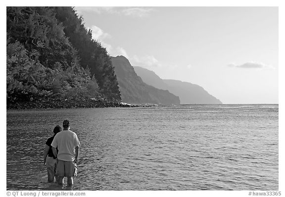 Couple standing in water, Kee Beach, late afternoon. Kauai island, Hawaii, USA