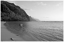 Couple standing in water looking at the Na Pali Coast, Kee Beach, late afternoon. Kauai island, Hawaii, USA ( black and white)