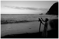 Hawaiian woman piles a stone on a stick as a traditional gesture of reverence, Polulu Beach. Big Island, Hawaii, USA (black and white)