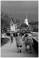 Beachgoers walking past ironman triathlon sign, Kailua-Kona. Hawaii, USA ( black and white)