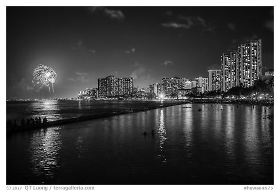 Watching fireworks from seawall, Kuhio Beach, Waikiki. Waikiki, Honolulu, Oahu island, Hawaii, USA (black and white)