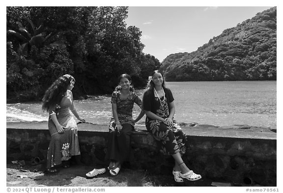 Samoan girls sitting on seawall, Fagasa. Tutuila, American Samoa (black and white)