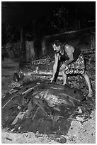 Candy Mann taking out banana leaves to uncover Umu earth oven, Tisa Barefoot Bar. Tutuila, American Samoa ( black and white)