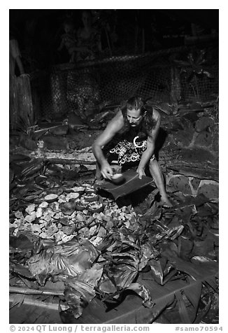 Man taking out foods prepared in Umu earth oven, Tisa Barefoot Bar. Tutuila, American Samoa (black and white)