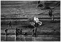 Children bathe in the river and dry out near a fire in a small hamlet. Mekong river, Laos (black and white)
