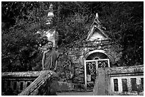 Novice Buddhist monk at entrance of cave, Pak Ou. Laos ( black and white)