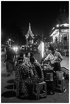 Women eating at street stall at night with Shwedagon Pagoda in background. Yangon, Myanmar ( black and white)