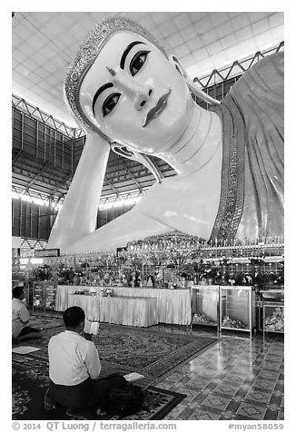 Men praying in front of reclining Buddha statue, Kyauk Htat Gyi Pagoda. Yangon, Myanmar (black and white)