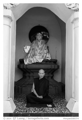 Monk meditating in alcove with Buddha statue, Shwedagon Pagoda. Yangon, Myanmar (black and white)