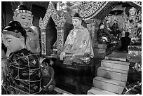 Woman and monk in pavillion surrounded by Buddha statues. Yangon, Myanmar ( black and white)