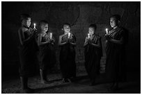 Five novices standing in circle inside temple with candles. Bagan, Myanmar ( black and white)