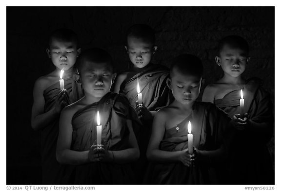 Young buddhist monks holding candles with eyes closed. Bagan, Myanmar (black and white)