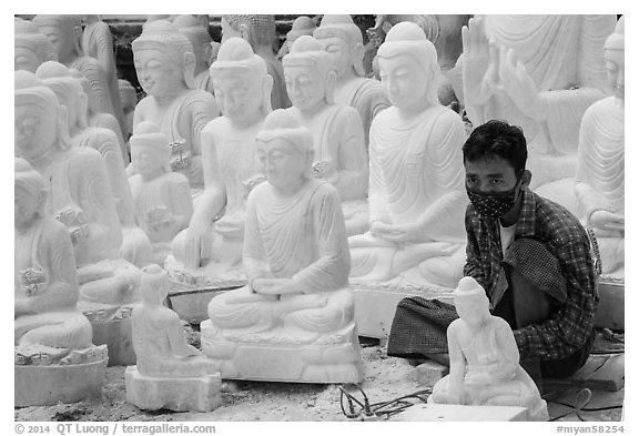 Man working amongst many  buddha statues on Marble street workshop. Mandalay, Myanmar (black and white)
