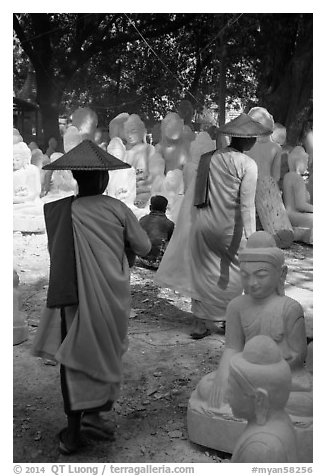 Nuns walk between buddha statues on Marble street. Mandalay, Myanmar (black and white)