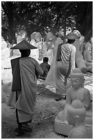 Nuns walk between buddha statues on Marble street. Mandalay, Myanmar ( black and white)