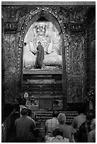 Monk applying gold leaf to Buddha statue in Mahamuni Pagoda. Mandalay, Myanmar ( black and white)
