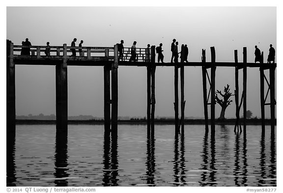 U Bein Bridge with monks and visitors strolling at dusk. Amarapura, Myanmar (black and white)