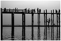 U Bein Bridge with monks and visitors strolling at dusk. Amarapura, Myanmar ( black and white)
