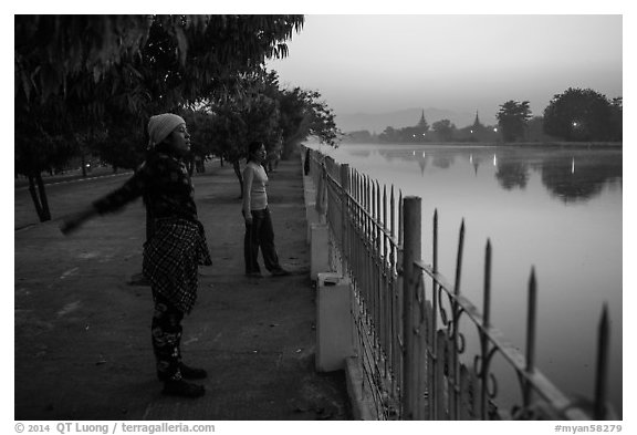 Women exercising next to Mandalay Fort at dawn. Mandalay, Myanmar (black and white)
