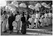 Umbrella bearer, Monks, and donation holders in alms procession. Mandalay, Myanmar ( black and white)