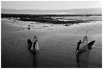 Intha fishermen row with backlit conical nets. Inle Lake, Myanmar ( black and white)