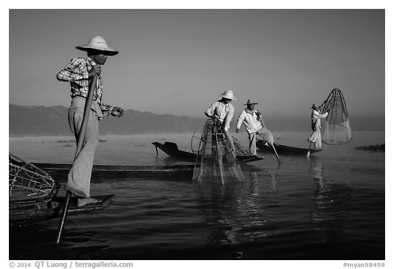 Intha fishermen standing on stern of their boats to fish. Inle Lake, Myanmar (black and white)