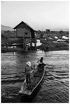 Children rowing across canal towards floating gardens, Maing Thauk Village. Inle Lake, Myanmar ( black and white)