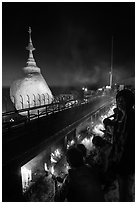 Pilgrims light up candles behind the Golden Rock at dusk. Kyaiktiyo, Myanmar ( black and white)