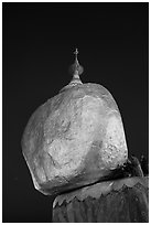 Pilgrims affix golden leaves to balancing boulder stupa at dawn. Kyaiktiyo, Myanmar ( black and white)
