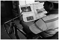Cyclo driver looking at picture of QT Luong tour group in newspaper. Bago, Myanmar ( black and white)