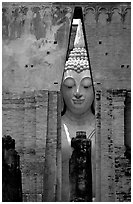 Monumental Buddha image seen between walls,  Wat Si Chum. Sukothai, Thailand ( black and white)