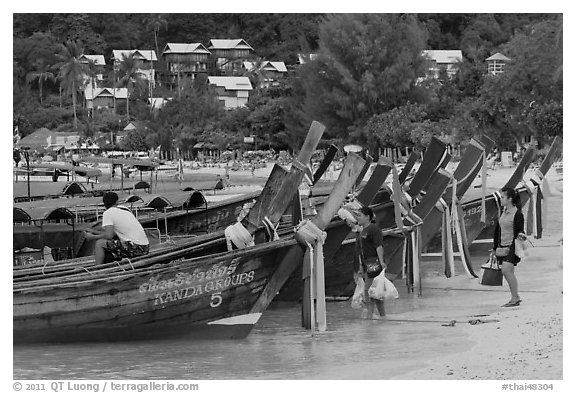 Women returning with shopping bags prepare to board boats, Ko Phi Phi. Krabi Province, Thailand (black and white)