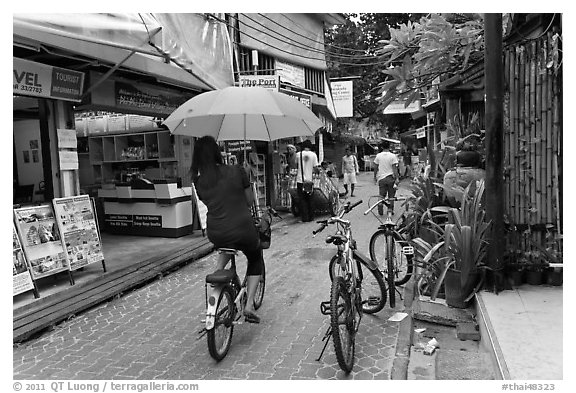 Woman riding bicycle with unbrella, Tonsai village, Ko Phi-Phi Don. Krabi Province, Thailand