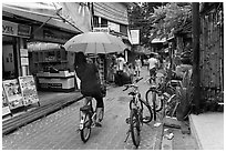 Woman riding bicycle with unbrella, Tonsai village, Ko Phi-Phi Don. Krabi Province, Thailand (black and white)