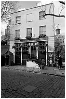 Cobblestone mews, pub, and man standing outside. London, England, United Kingdom (black and white)