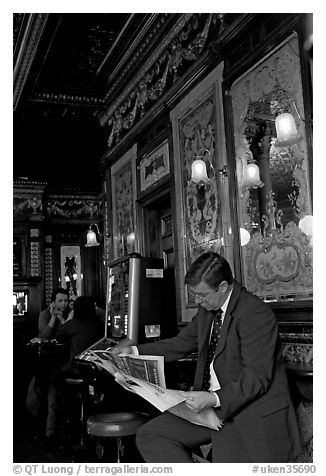 Man reading newspaper in front of etched mirrors, pub Princess Louise. London, England, United Kingdom (black and white)