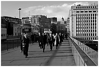 Office workers pouring out of the city of London across London Bridge, late afternoon. London, England, United Kingdom ( black and white)
