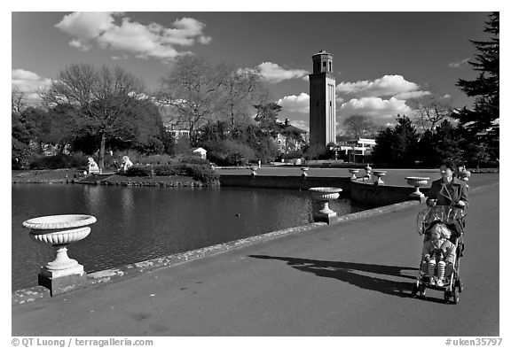 Woman pushing stroller next to the lake. Kew Royal Botanical Gardens,  London, England, United Kingdom (black and white)