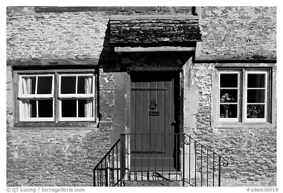 Windows and doorway entrance of stone house, Lacock. Wiltshire, England, United Kingdom (black and white)