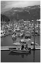Small boat loaded at pier, harbor, and mountains. Whittier, Alaska, USA ( black and white)